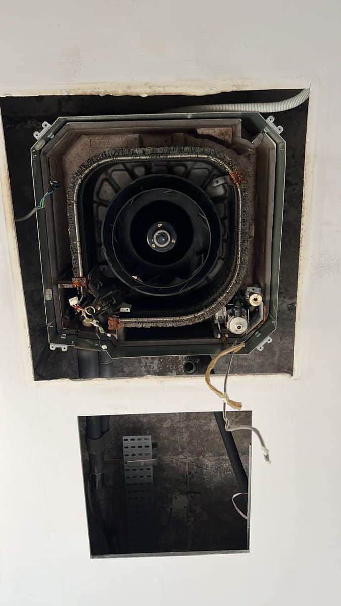 Ceiling cassette aircon with its grille removed, the fan exposed for servicing