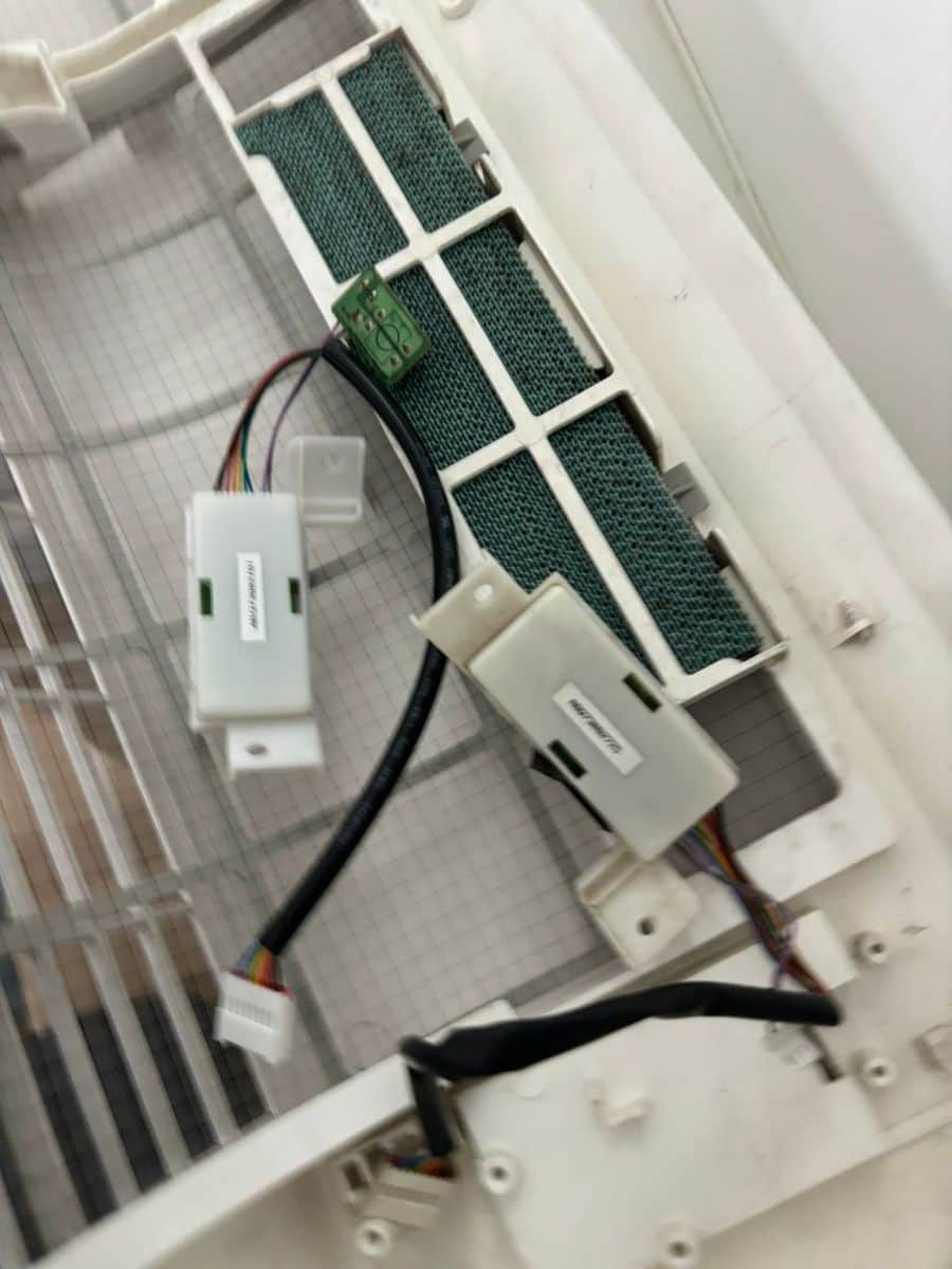 Wall-mounted aircon opened up with its filters and front cover off for servicing